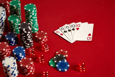 Kumarhane kumarhanesi poker ekipmanları ve eğlence konsepti. Kırmızı arka planda kart ve fiş oyunlarının kapanışı. Dolu Ev