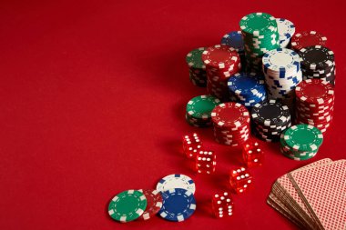 Kırmızı arka planda poker fişleri ve kart destesi. Farklı poker fişleri grubu. Kumarhane geçmişi.