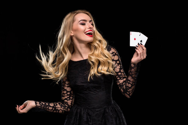 Beautiful young woman holding two ace of cards in her hand isolated on black background