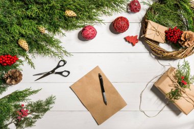 Noel dekorlu ardıç dalları. Noel, yeni yıl geçmişi. Ardıç ağacının kozalaklı dalları, bir yaprak kraft kağıdı ve bir kalem..