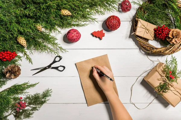 Ветки можжевельника с рождественским декором. Рождество, Новый год. Хвойные ветви можжевельника, лист крафтовой бумаги и ручка. — стоковое фото