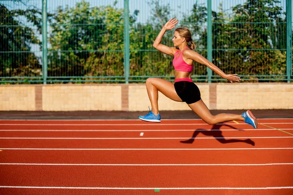 Side view beautiful young woman exercise jogging and running on athletic track on stadium — Stock Photo, Image