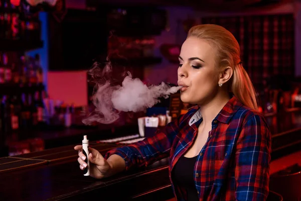 Joven bonita mujer fumar un cigarrillo electrónico en la barra de vapor — Foto de Stock