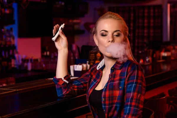 Jovem mulher bonita fuma um cigarro eletrônico no bar vape — Fotografia de Stock