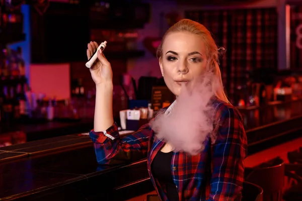 Młoda piękna kobieta pali elektronicznego papierosa w vape bar — Zdjęcie stockowe