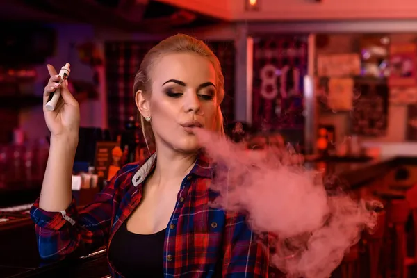 Молода красива жінка курить електронну сигарету у вейп-барі — стокове фото