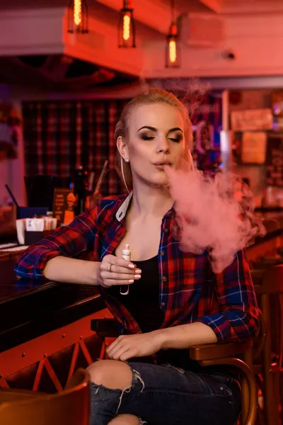 Joven bonita mujer fumar un cigarrillo electrónico en la barra de vapor —  Fotos de Stock
