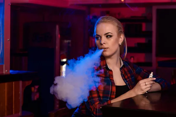 Kafesteki tişörtlü güzel bir kadın Vape Bar 'da elektronik sigara içiyor. — Stok fotoğraf