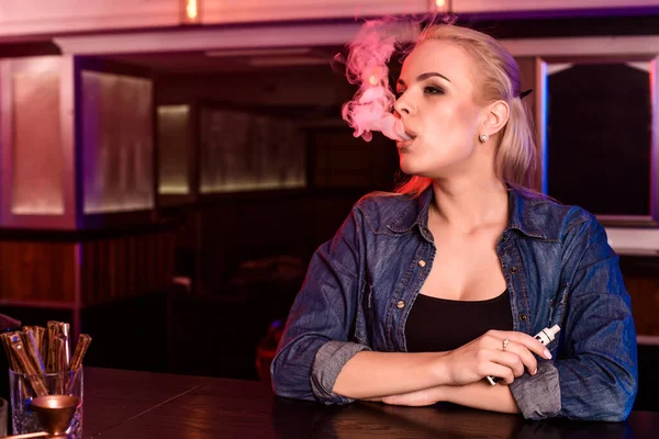 年轻漂亮的女人在蒸汽吧抽一支电子香烟 — 图库照片