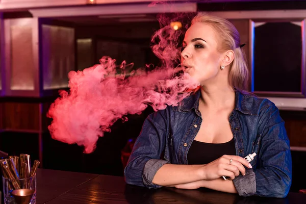 Jovem mulher bonita fuma um cigarro eletrônico no bar vape — Fotografia de Stock