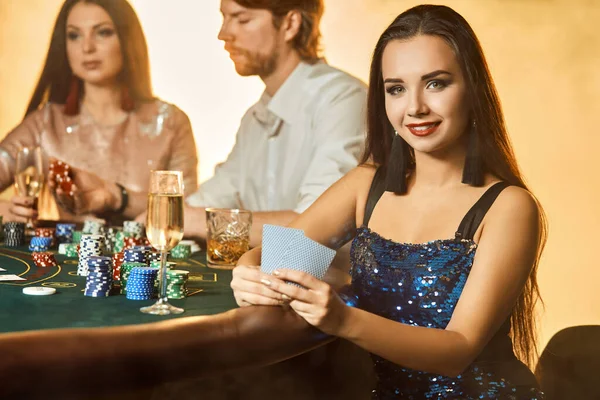 Skupina elegantních lidí hrajících poker v herně. Zaměřte se na luxusní brunetku v modrých lesklých šatech — Stock fotografie