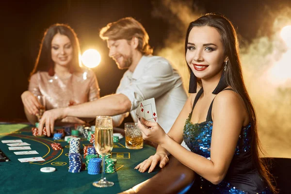 Skupina elegantních lidí hrajících poker v herně. Zaměřte se na emocionální brunetku v modrých lesklých šatech — Stock fotografie
