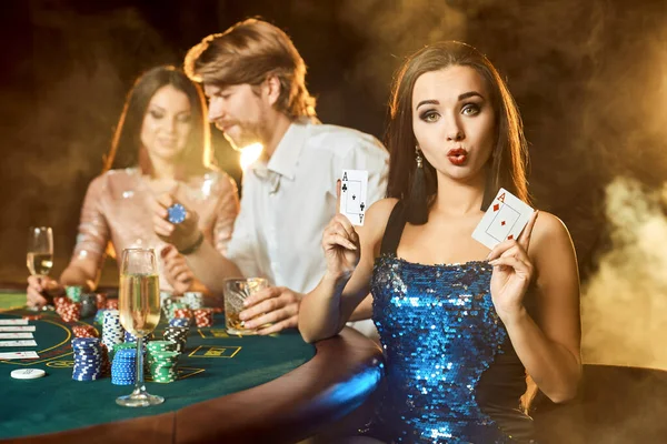 Grupp av en elegant människor som spelar poker på spelhuset. Fokusera på en känslomässig brunett i en blå glänsande klänning — Stockfoto