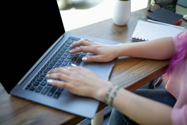 Arkadan görünüşü kafede otururken boş kopya alanı ekranlı dizüstü bilgisayarda klavye bir genç pembe saçlı kadın.