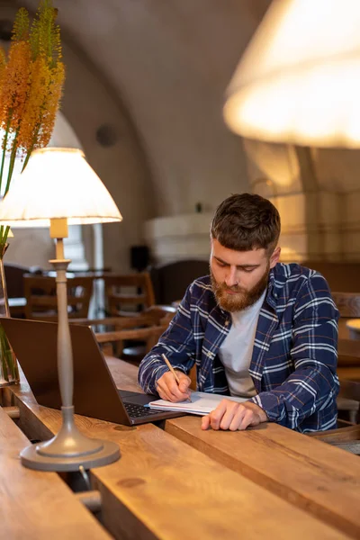 Случайный бизнесмен или фрилансер, планирующий свою работу над ноутбуком, работающий на ноутбуке со смартфоном, чашкой кофе на столе в кафе или домашнем офисе . — стоковое фото
