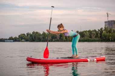 Yoga pozisyonu almış sporcu bir kadın, yemek masasında yoga yapıyor, esneklik ve kas esnekliği için egzersiz yapıyor.
