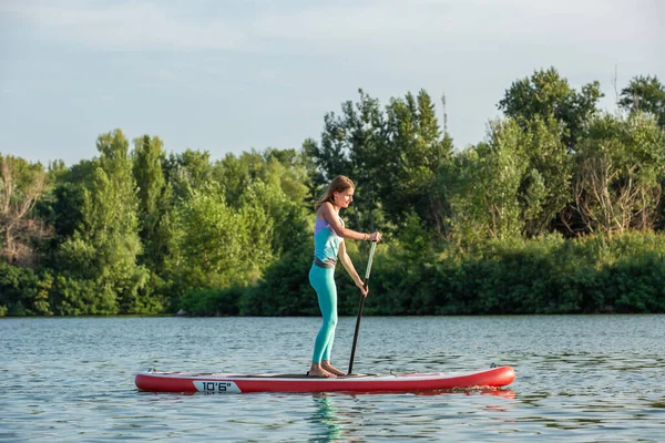 Pewnie kobieta stoi z wiosłem na deski surfingowej, Sup — Zdjęcie stockowe