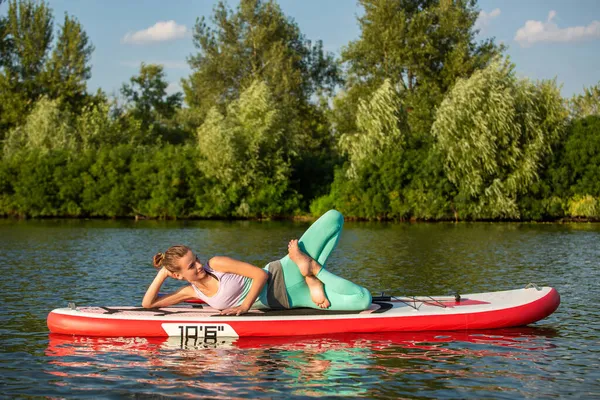 Frau praktiziert morgens Yoga auf dem Paddelbrett — Stockfoto