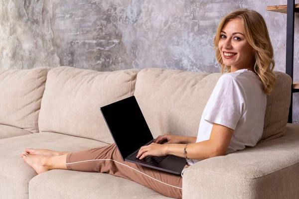 Nő a kanapé makett üres képernyő a laptop dolgozik. Üres másolat monitor hirdetés hely. Fekete képernyő. — Stock Fotó