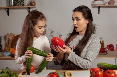 Anne ve kızı sebze salatası yapıyor ve mutfakta eğleniyor.