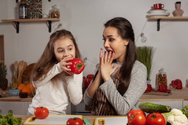 Anne ve kızı sebze salatası yapıyor ve mutfakta eğleniyor.
