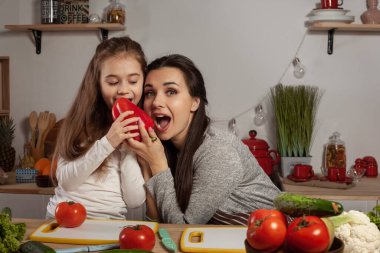 Anne ve kızı sebze salatası yapıyor ve mutfakta eğleniyor.
