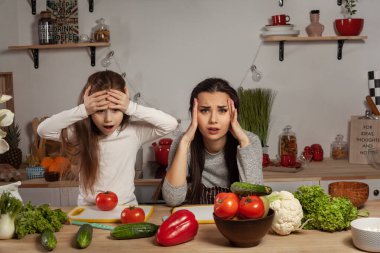 Anne ve kızı sebze salatası yapıyor ve mutfakta eğleniyor.
