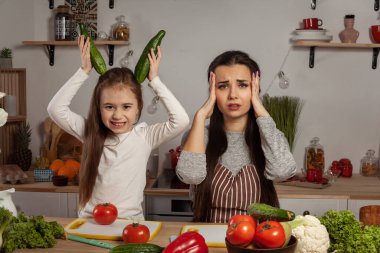 Anne ve kızı sebze salatası yapıyor ve mutfakta eğleniyor.