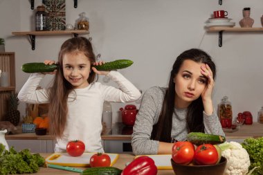 Anne ve kızı sebze salatası yapıyor ve mutfakta eğleniyor.