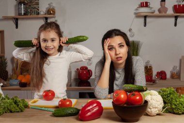 Anne ve kızı sebze salatası yapıyor ve mutfakta eğleniyor.