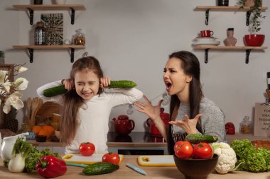 Anne ve kızı sebze salatası yapıyor ve mutfakta eğleniyor.
