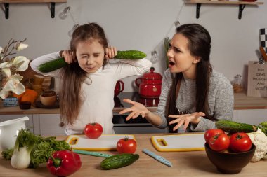 Anne ve kızı sebze salatası yapıyor ve mutfakta eğleniyor.