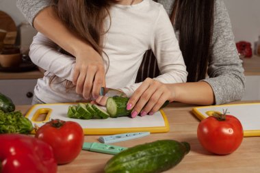 Anne ve kızı sebze salatası yapıyor ve mutfakta eğleniyor.
