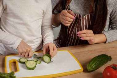 Anne ve kızı sebze salatası yapıyor ve mutfakta eğleniyor.