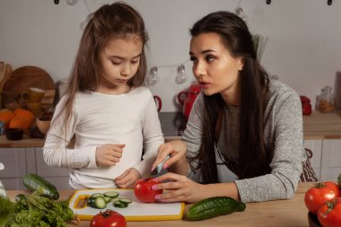 Anne ve kızı sebze salatası yapıyor ve mutfakta eğleniyor.