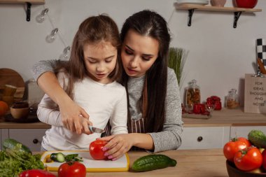 Anne ve kızı sebze salatası yapıyor ve mutfakta eğleniyor.
