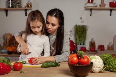 Anne ve kızı sebze salatası yapıyor ve mutfakta eğleniyor.