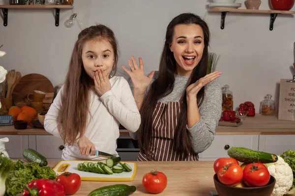 Anne ve kızı sebze salatası yapıyor ve mutfakta eğleniyor.