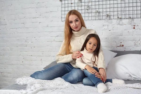 Mãe e sua filha criança menina brincando e abraçando na cama — Fotografia de Stock