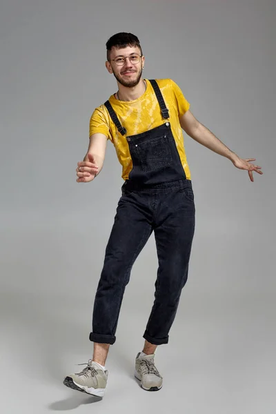 Pełnowymiarowy portret zabawnego faceta tańczącego w studio na szarym tle. — Zdjęcie stockowe