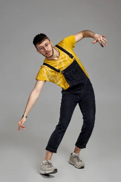 Ganzkörperporträt eines lustigen Typen, der im Studio auf grauem Hintergrund tanzt. — Stockfoto