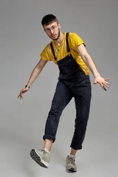 회색 배경으로 스튜디오에서 춤추고 있는 웃긴 남자의 전신 사진. — 스톡 사진