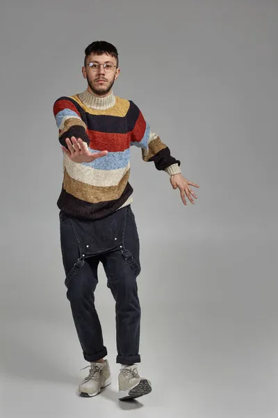 Full-length portrait of a funny guy dancing in studio on a gray background. — Stock Photo, Image