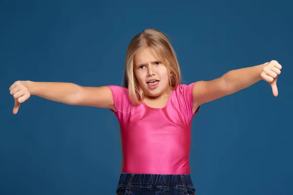 Портрет эмоциональной выразительной маленькой девочки на синем фоне — стоковое фото