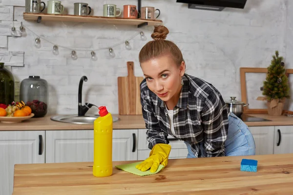 Young woman or housewife in rubber gloves wiping table with microfiber cloth at home kitchen. — Stock Photo, Image