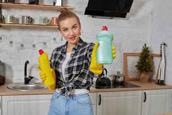 Vrouw vergelijken wasmiddel producten, ze houdt twee flessen en controleer ze thuis keuken. — Stockfoto