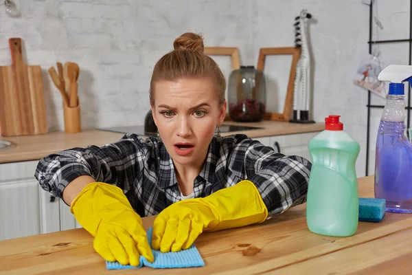 Jonge vrouw in beschermende handschoenen veegt een tafel in de keuken met een doek — Stockfoto