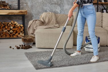 Güzel genç kadının evde halı temizlerken elektrik süpürgesi kullanarak kırpılmış görüntü