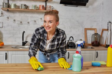 Lastik eldivenli genç kadın ya da ev hanımı mutfak mutfağında mikrofiber bezle masayı siliyor..