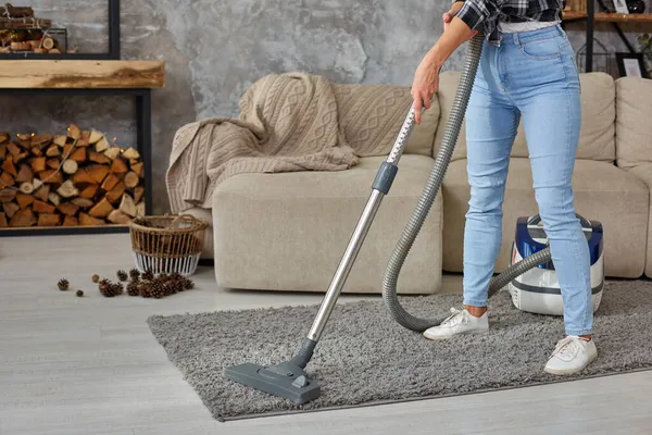 Imagen recortada de una hermosa mujer joven usando una aspiradora mientras limpia la alfombra en la casa — Foto de Stock